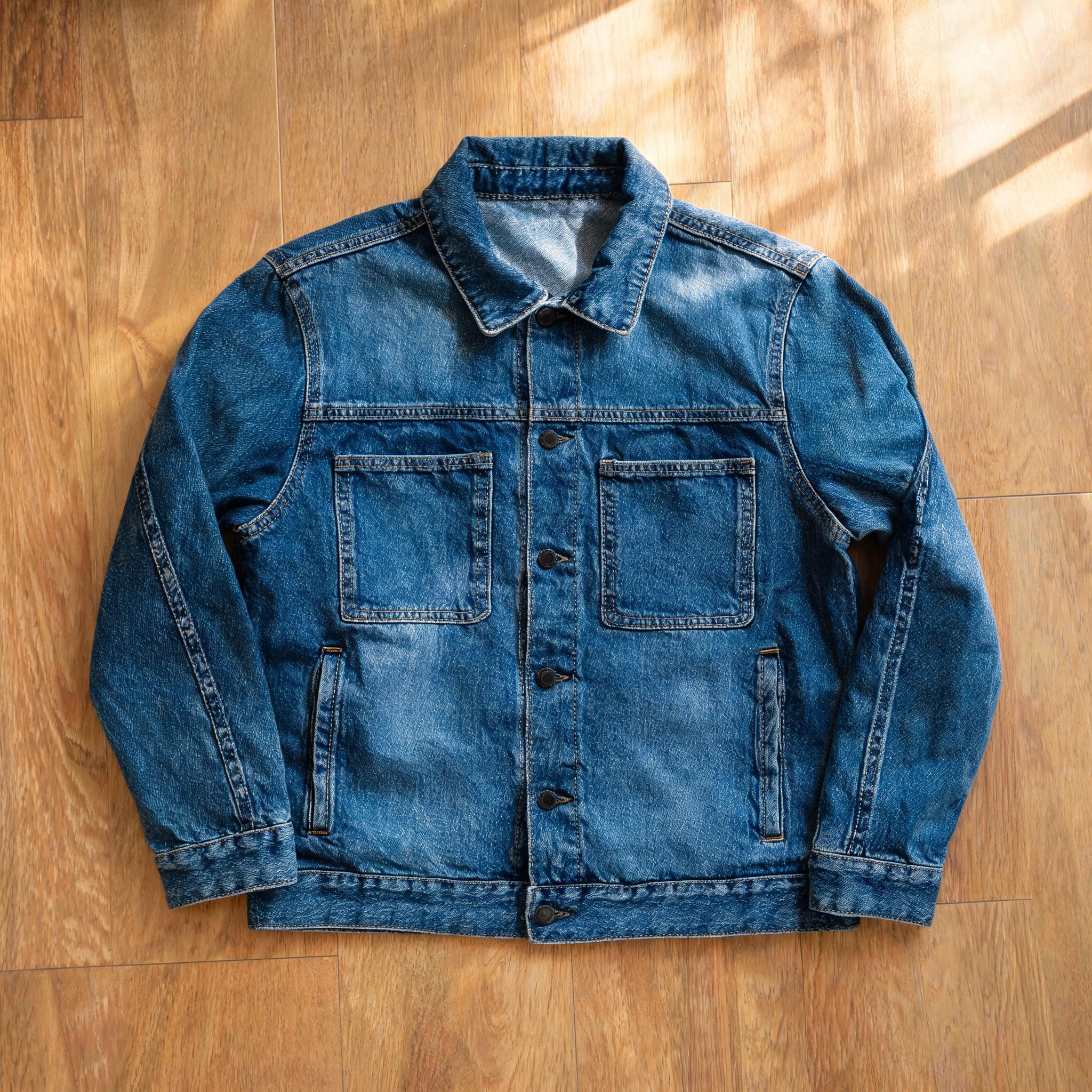 A denim jacket photographed as a flat lay on a wooden floor — the raw product image before AI fashion model generation